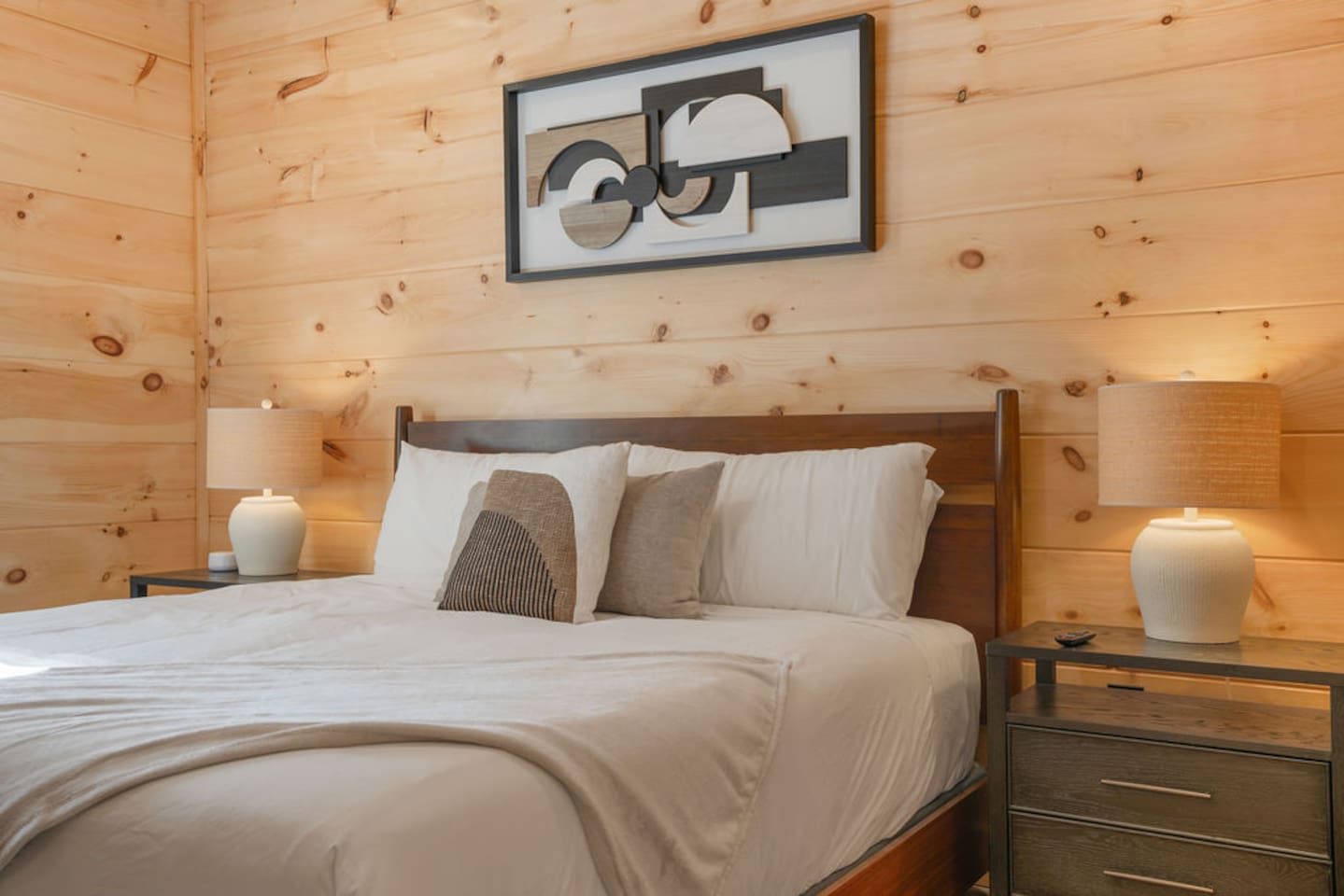 King bedroom with wood-paneled walls, nightstands, and lamps