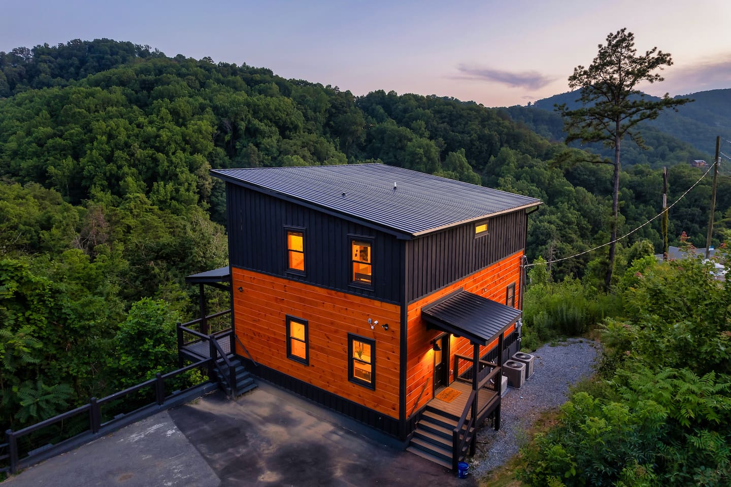 Sugar Splash cabin exterior at dusk with a forested mountain backdrop
